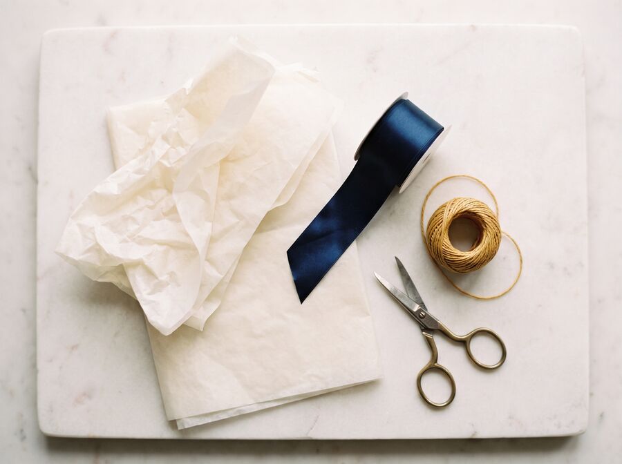Ręczne pakowanie prezentu — papier, wstążka i monogram